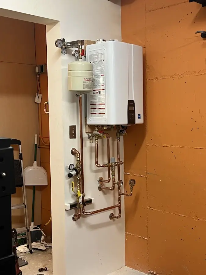 Plumbing technician inspecting water heater connections in Wheatfield